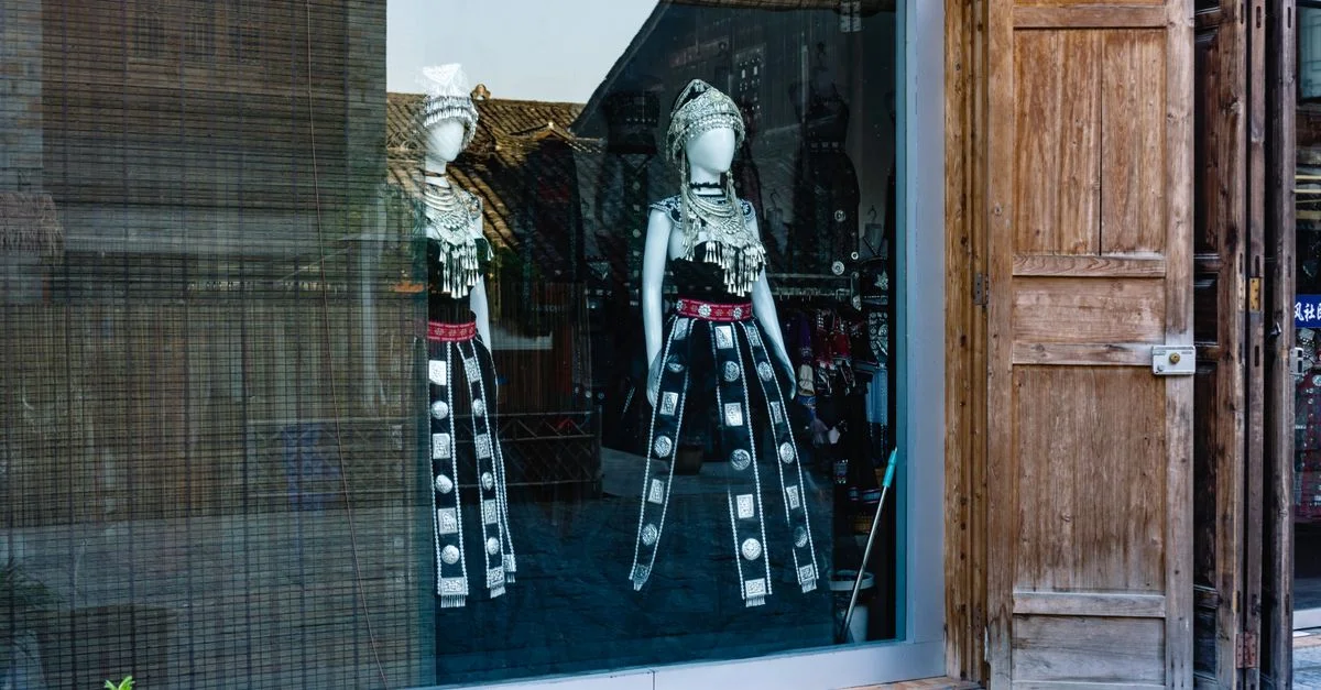 Vêtements traditionnels dans la vitrine d'un magasin présentant des tenues culturelles uniques.