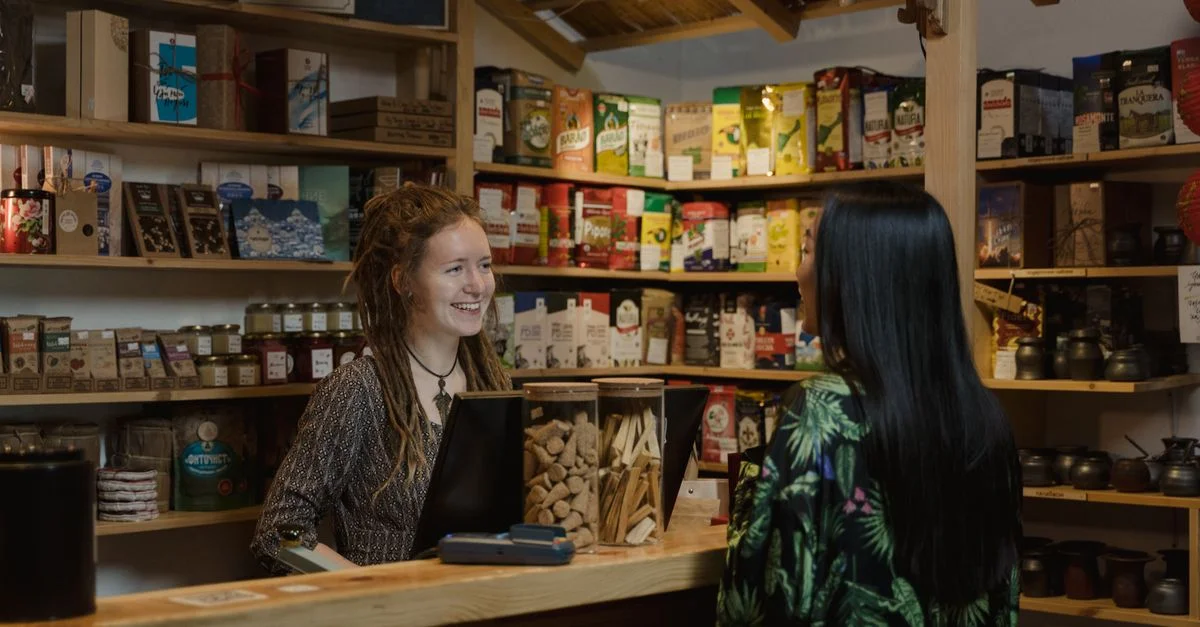 Commerçant amical aidant un client dans une ambiance de magasin confortable et bien approvisionné.