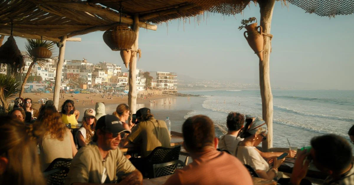 Un café paisible en bord de mer marocain, où les gens profitent du coucher de soleil sur l'océan.