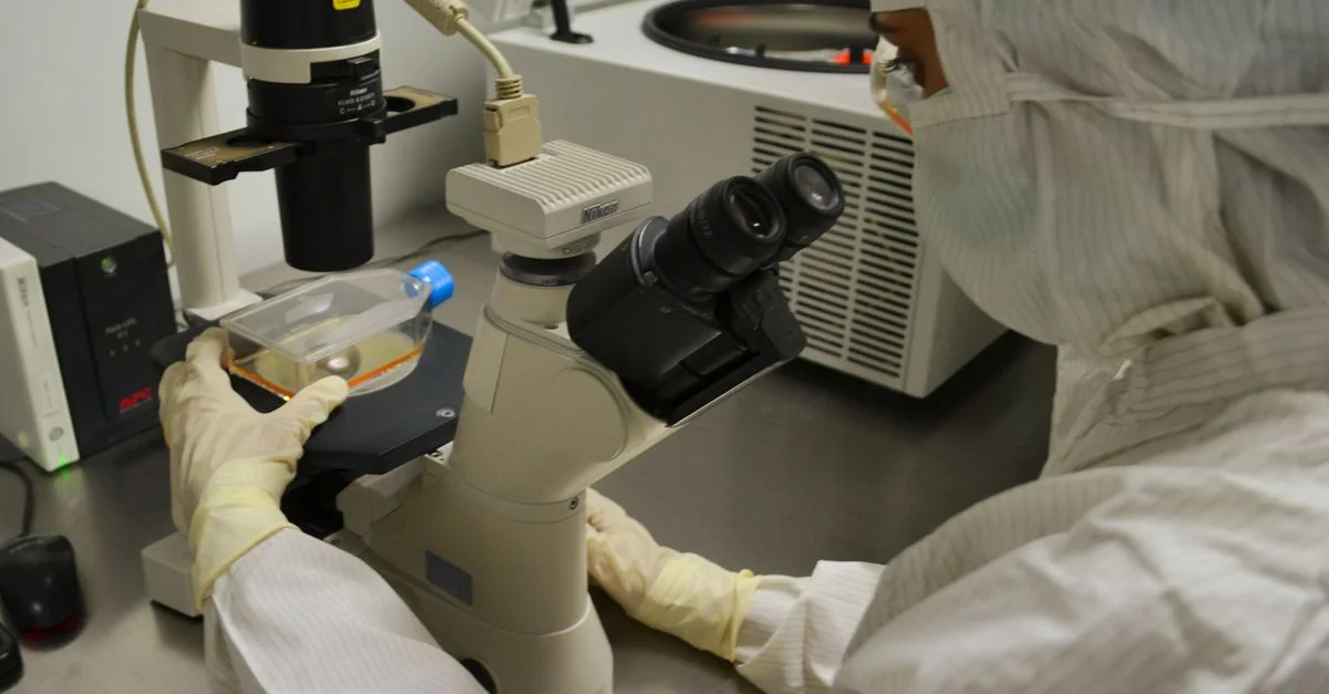 Professionnel de la santé examinant un échantillon sous microscope dans un cadre de laboratoire.