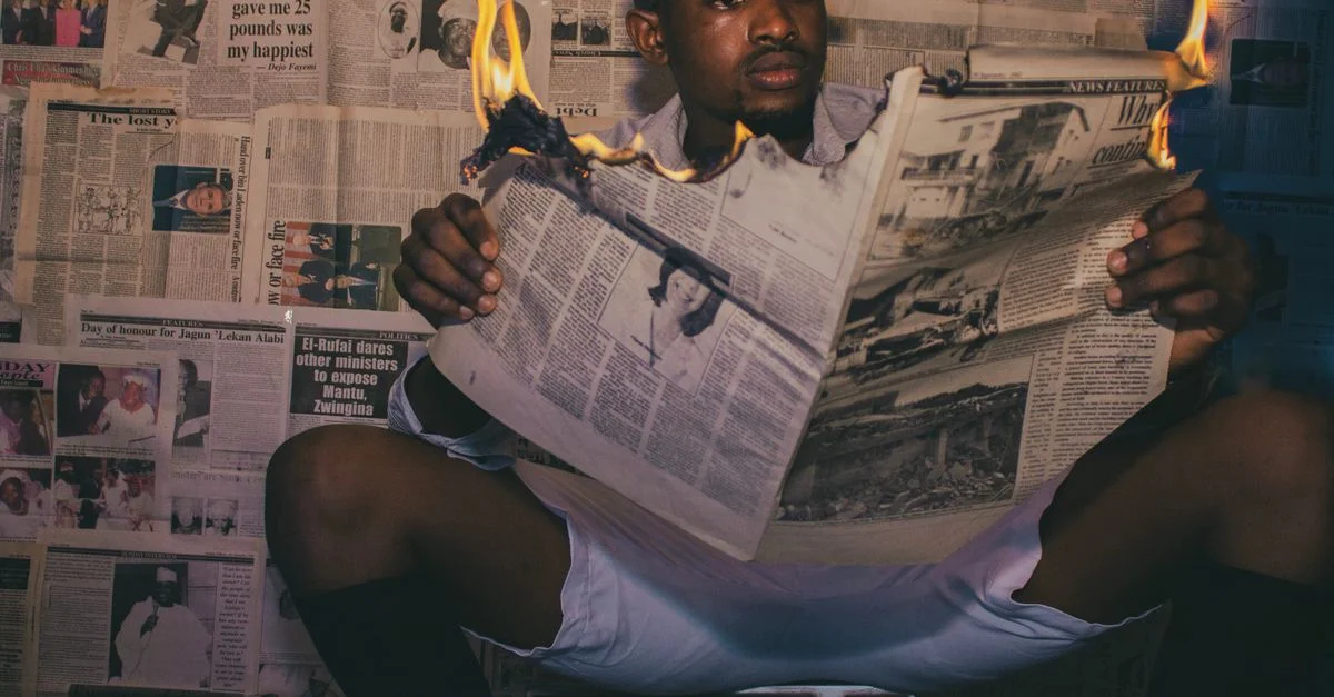Un homme lit un journal qui brûle dans une pièce classique au décor vintage et équipée d'une télévision rétro.