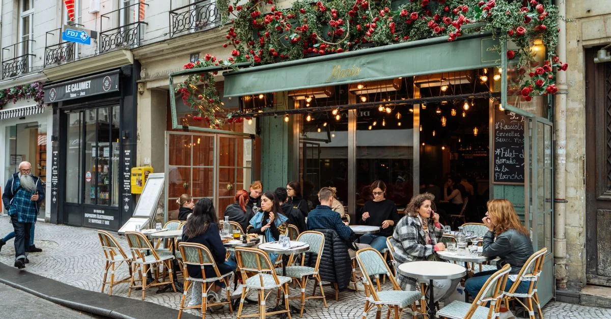 Une scène de rue animée d'un café parisien avec une ambiance extérieure et une restauration dynamiques.