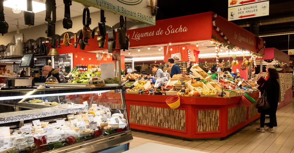 Scène de marché intérieur animée à Avignon, capturant des étals divers et des produits colorés.