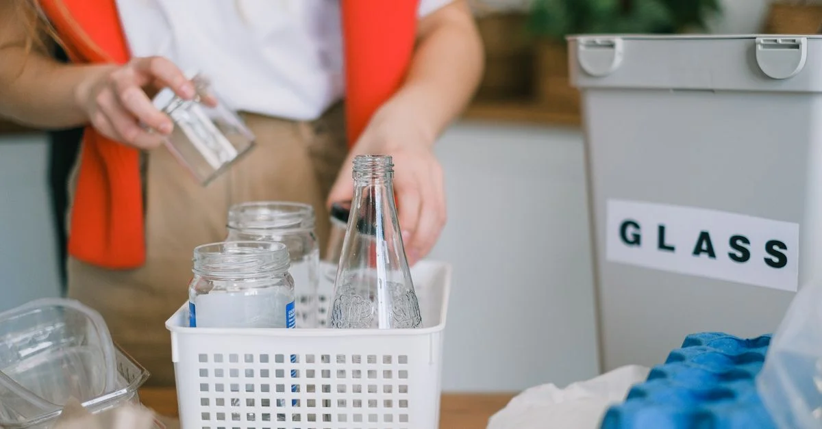 Une femme trie le verre pour le recyclage à la maison avec des bacs, promouvant des pratiques respectueuses de l'environnement.