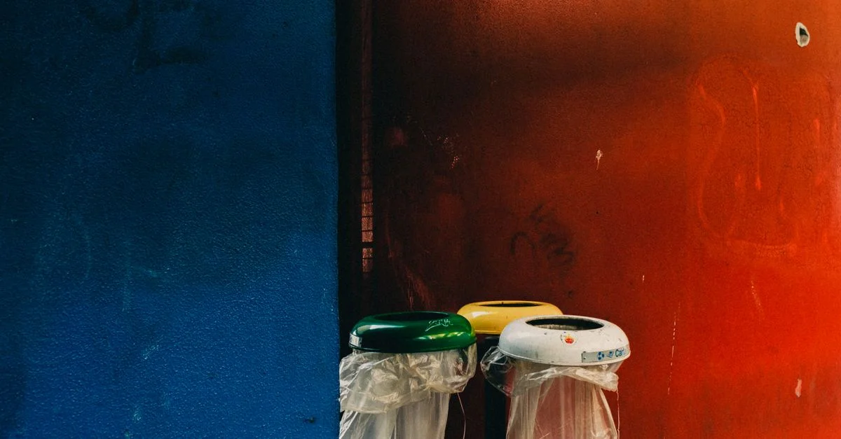 Bacs de recyclage en plastique contre des murs vibrants bleu et rouge dans un cadre urbain.