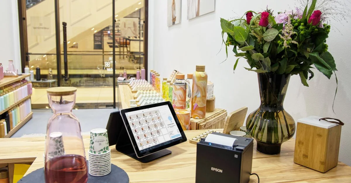 Un comptoir de caisse élégant avec un bouquet de fleurs et un système de paiement numérique.