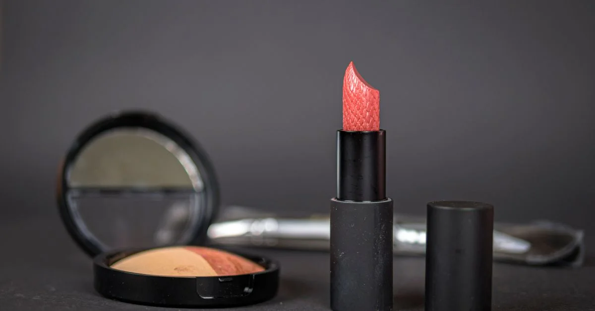 Rouge à lèvres noir et blush compact sur fond sombre, mettant en valeur les essentiels du maquillage élégant.