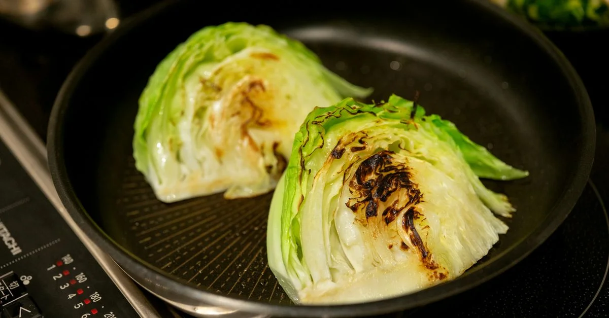 Gros plan sur des quartiers de chou grillés dans une poêle sur une cuisinière.